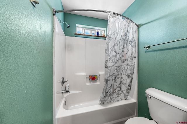 bathroom with shower / bath combo with shower curtain, toilet, and a textured wall