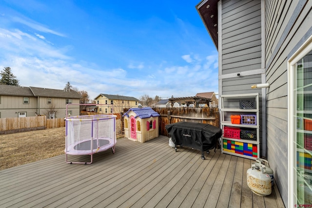 wooden terrace featuring a trampoline, fence, a pergola, and a grill