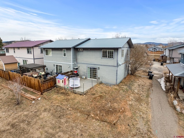 rear view of house with a patio area, central AC unit, metal roof, and fence