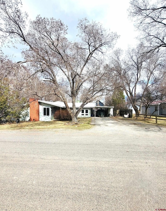 view of front facade featuring an attached carport, a front lawn, and driveway