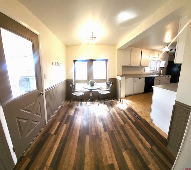 unfurnished dining area featuring a wainscoted wall, visible vents, a notable chandelier, a sink, and wood finished floors