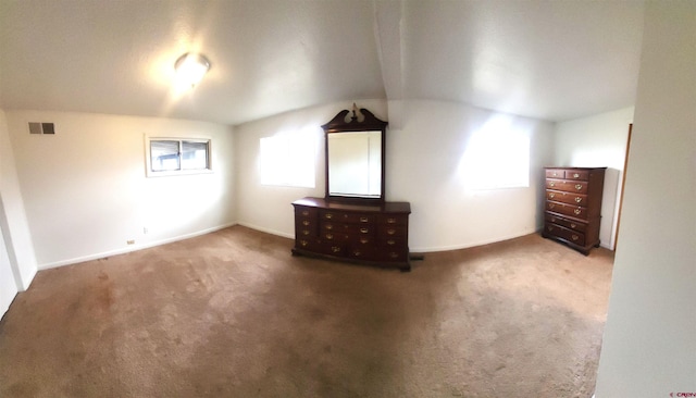 unfurnished bedroom featuring visible vents, lofted ceiling, carpet, and baseboards