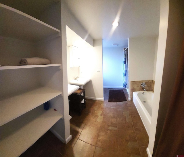 bathroom with vanity, a bath, baseboards, and a stall shower