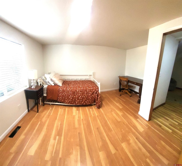 bedroom featuring wood finished floors, visible vents, and baseboards