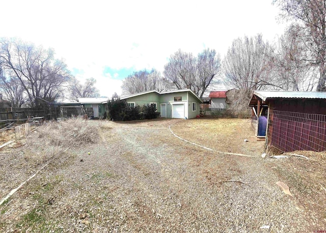 exterior space with metal roof, a garage, and fence