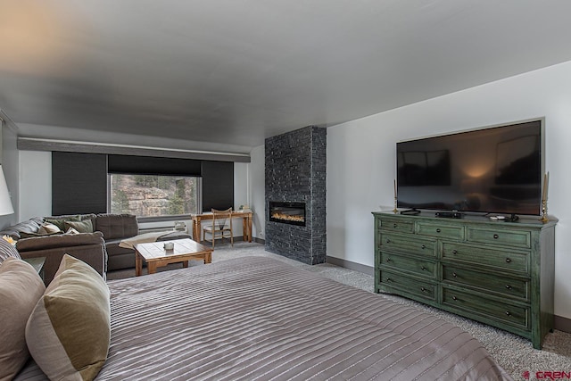 bedroom with baseboards, a large fireplace, and carpet floors