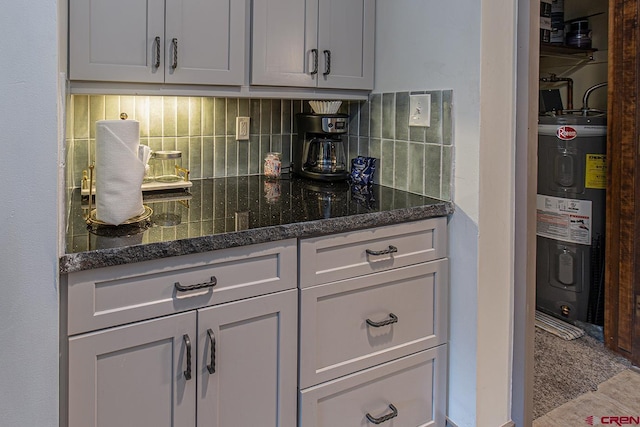 kitchen featuring dark stone counters, tasteful backsplash, and water heater