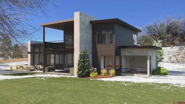 snow covered rear of property featuring a patio, a balcony, and a yard