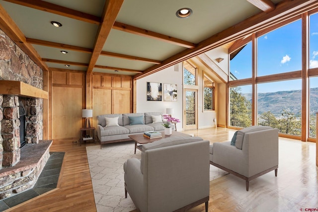 living area featuring beam ceiling, a mountain view, light wood-style flooring, and a fireplace