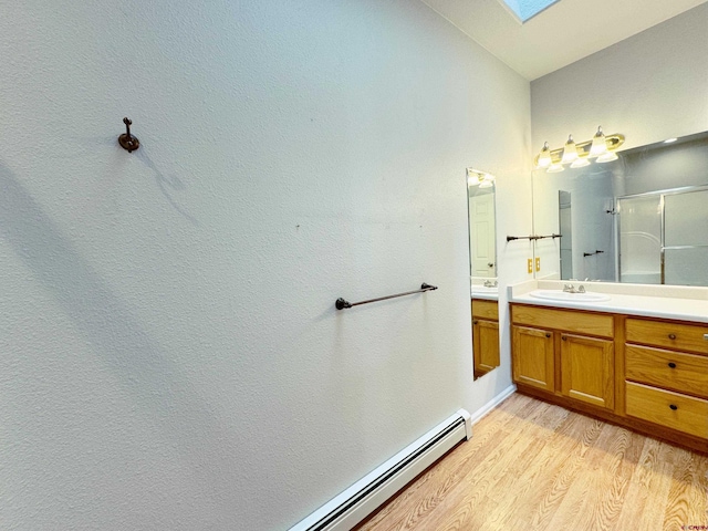 bathroom with lofted ceiling with skylight, a stall shower, wood finished floors, baseboards, and vanity