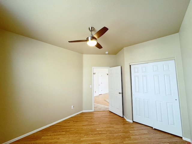 unfurnished bedroom featuring a closet, baseboards, light wood-style flooring, and a ceiling fan