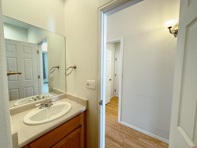 bathroom featuring baseboards, wood finished floors, and vanity