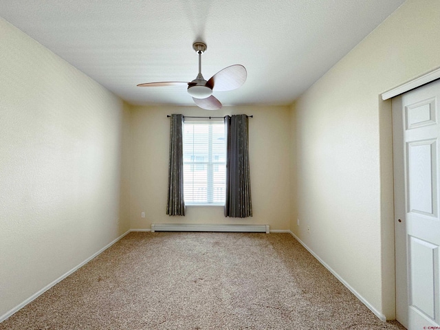 carpeted empty room featuring a baseboard heating unit, baseboards, and ceiling fan