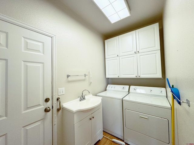 laundry room featuring a sink, cabinet space, light wood-style floors, and separate washer and dryer