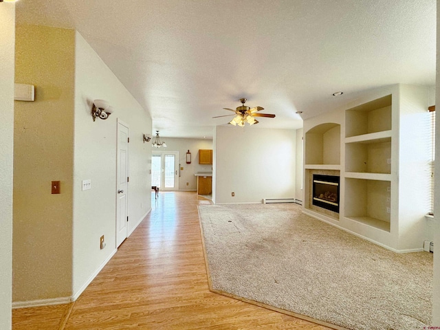 unfurnished living room with light wood-type flooring, built in shelves, a ceiling fan, a textured ceiling, and a glass covered fireplace