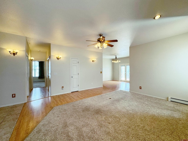 unfurnished living room with baseboards, light wood finished floors, light colored carpet, and ceiling fan with notable chandelier