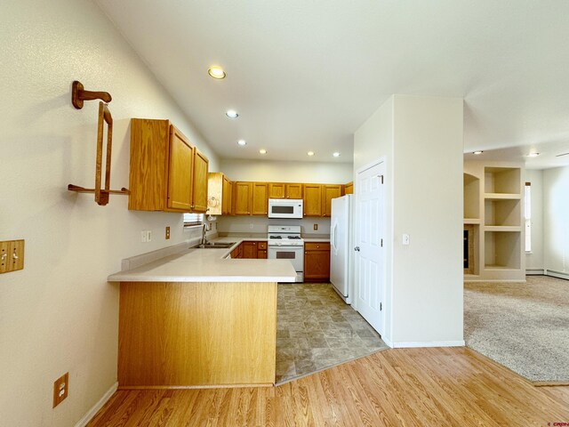 kitchen featuring a sink, open floor plan, white appliances, light wood-style floors, and light countertops