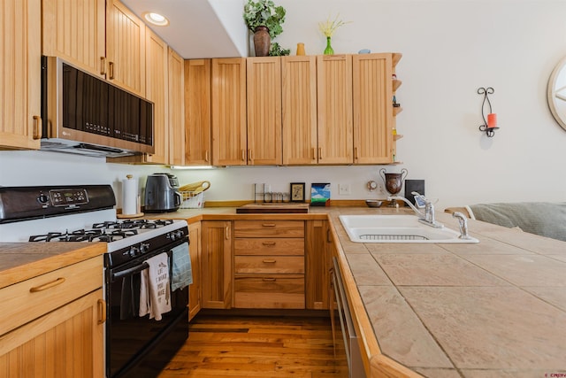 kitchen featuring dishwashing machine, gas stove, a sink, tile counters, and stainless steel microwave