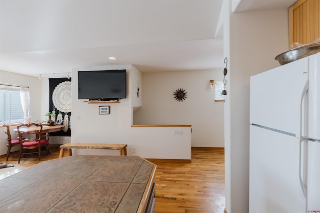 kitchen featuring light wood finished floors, baseboards, tile counters, recessed lighting, and freestanding refrigerator