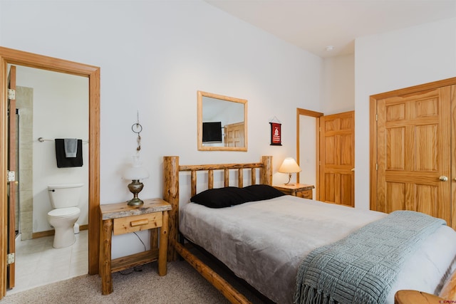 bedroom with light tile patterned floors, baseboards, light colored carpet, and ensuite bathroom