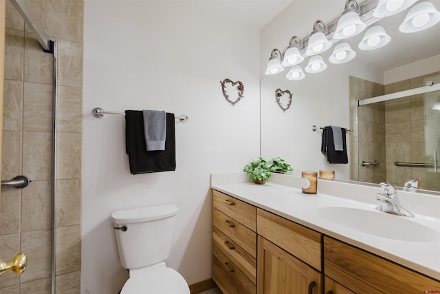 bathroom with a tile shower, toilet, and vanity