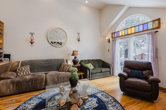 living area with wood finished floors, visible vents, and high vaulted ceiling