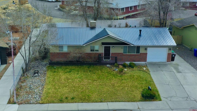 view of front of house featuring brick siding, a front lawn, metal roof, driveway, and an attached garage