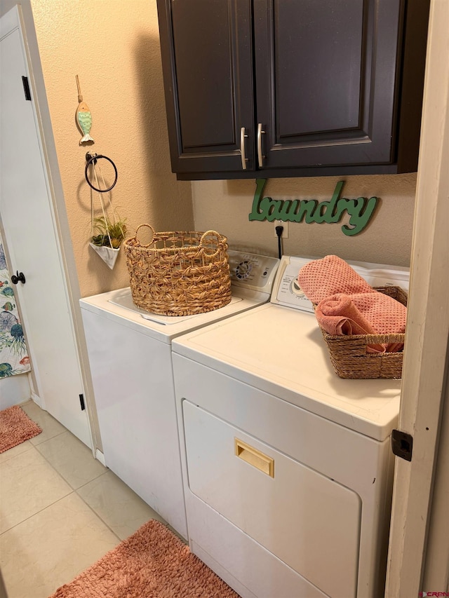 laundry area featuring washer and clothes dryer, cabinet space, and light tile patterned flooring