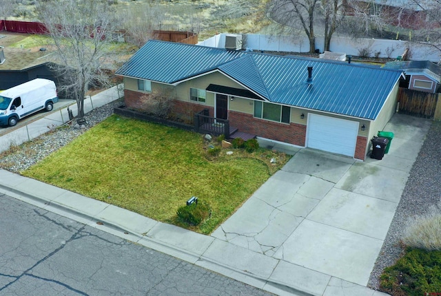 view of front of house with brick siding, a front lawn, fence, concrete driveway, and an attached garage