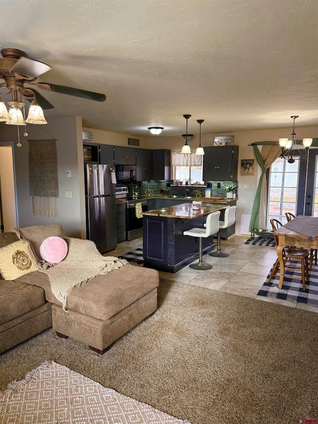 living area with light tile patterned floors and ceiling fan with notable chandelier