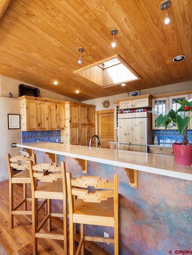 kitchen with recessed lighting, vaulted ceiling with skylight, wood ceiling, and light countertops