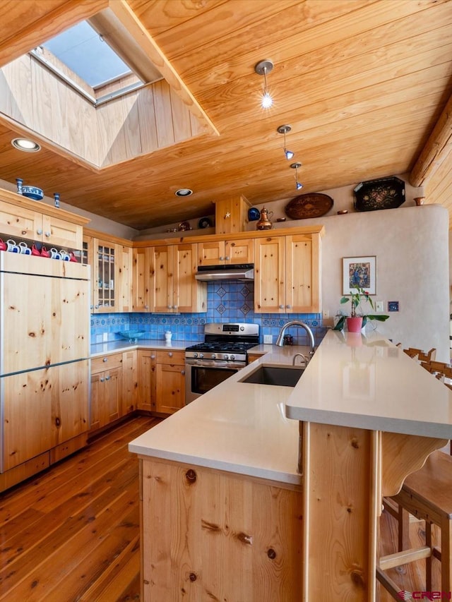 kitchen featuring a sink, light brown cabinetry, a peninsula, and stainless steel gas range