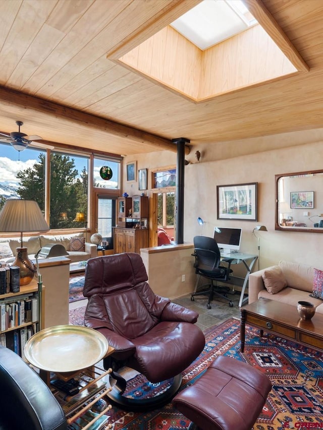 living area with wooden ceiling, a wood stove, plenty of natural light, and a ceiling fan