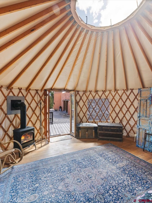 miscellaneous room featuring vaulted ceiling, a wood stove, and wood finished floors