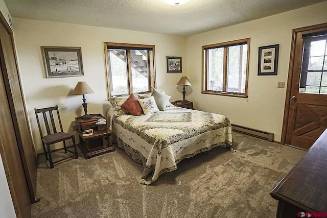 bedroom featuring a baseboard heating unit, carpet, and a textured ceiling