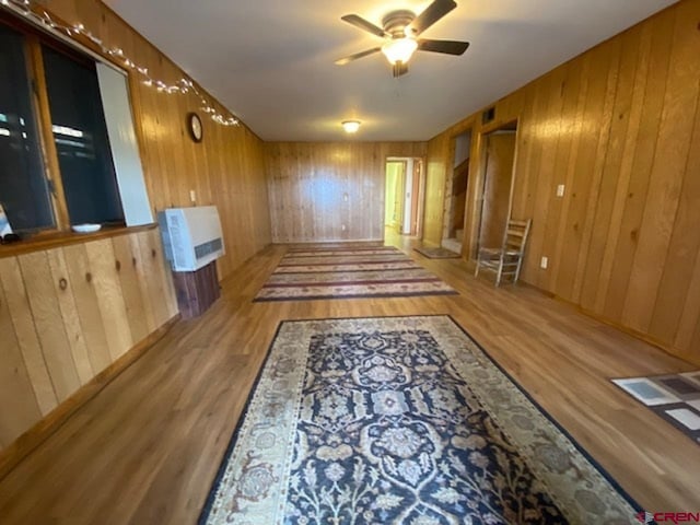 interior space with wooden walls, wood finished floors, and a ceiling fan