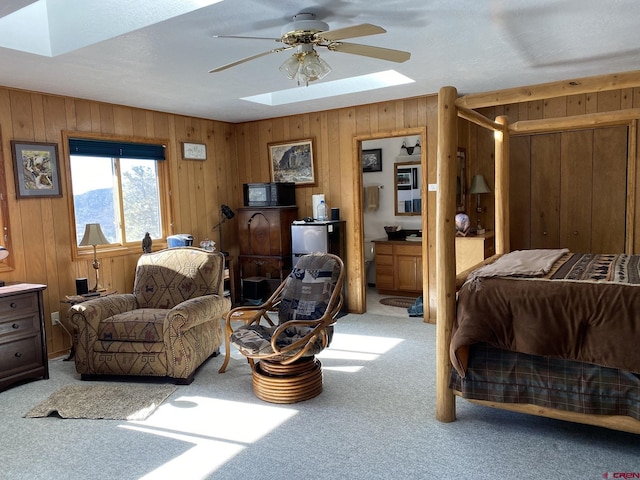 bedroom with light colored carpet, a skylight, and wooden walls