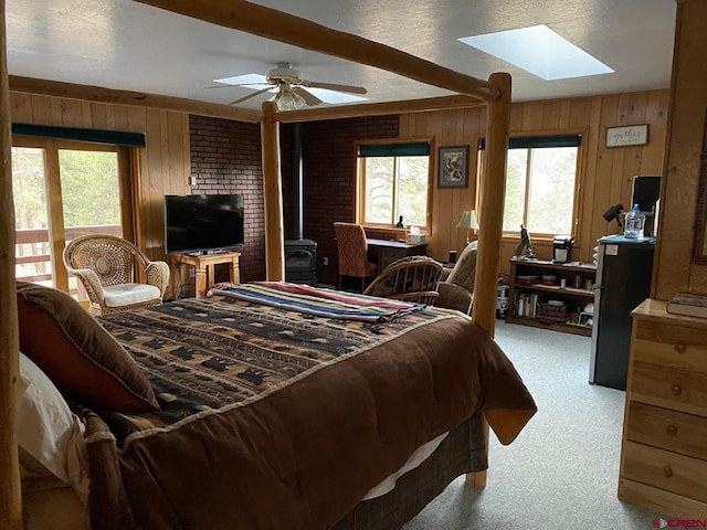 bedroom featuring a skylight, multiple windows, carpet, and a wood stove