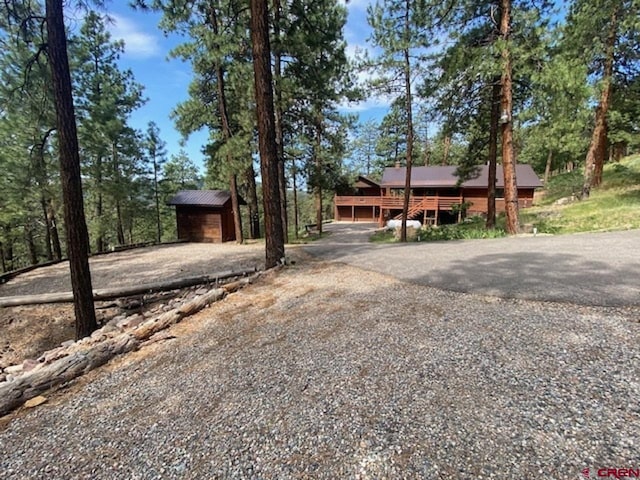 rustic home featuring an outdoor structure, driveway, and a shed