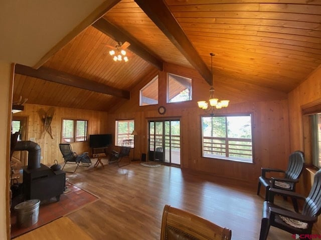 living room featuring wooden walls, vaulted ceiling with beams, wood finished floors, and a wood stove