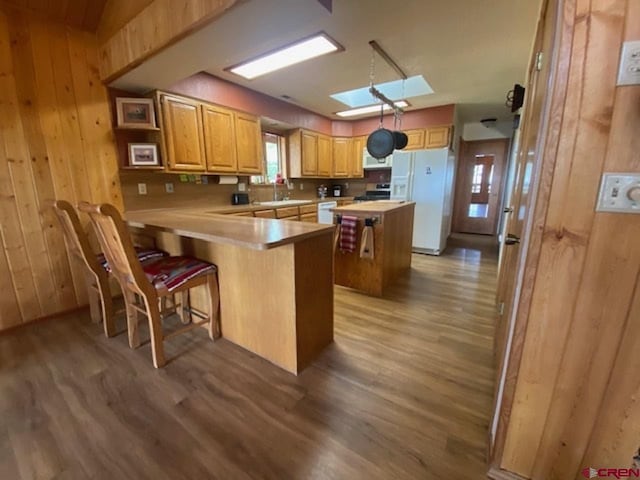 kitchen with white appliances, wooden walls, wood finished floors, and light countertops