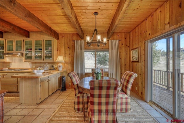 dining room featuring beam ceiling, wooden walls, an inviting chandelier, light tile patterned floors, and wood ceiling