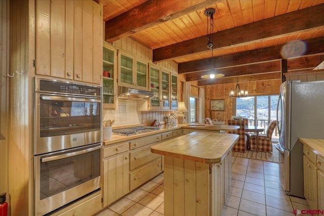 kitchen featuring wooden walls, a peninsula, butcher block countertops, under cabinet range hood, and appliances with stainless steel finishes