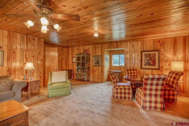 carpeted living room with wooden walls, wood ceiling, and ceiling fan