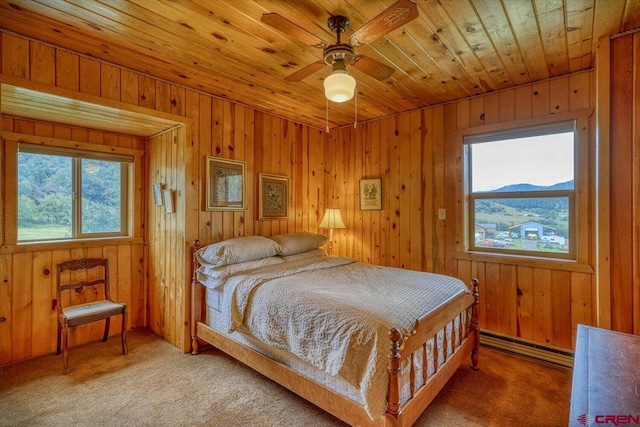 bedroom featuring baseboard heating, carpet flooring, wood ceiling, and wooden walls