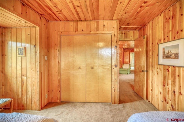 unfurnished bedroom featuring wooden ceiling, carpet flooring, and wood walls