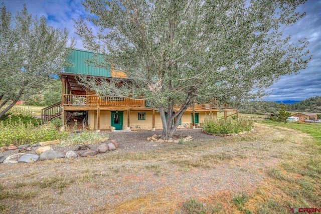 rear view of property featuring stairs, metal roof, and a wooden deck