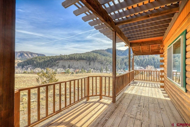 wooden terrace with a mountain view, a wooded view, and a pergola