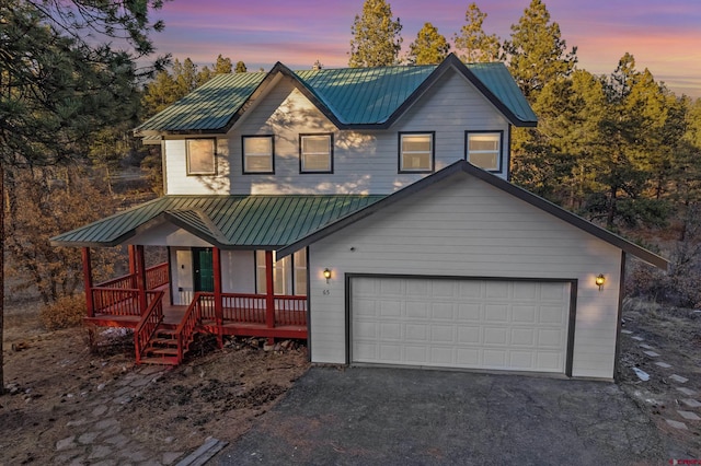 chalet / cabin with metal roof, a garage, and driveway