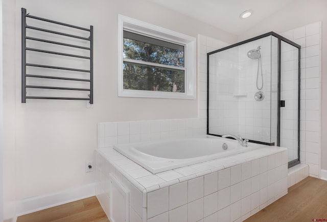 full bathroom featuring baseboards, radiator heating unit, a garden tub, a stall shower, and wood finished floors